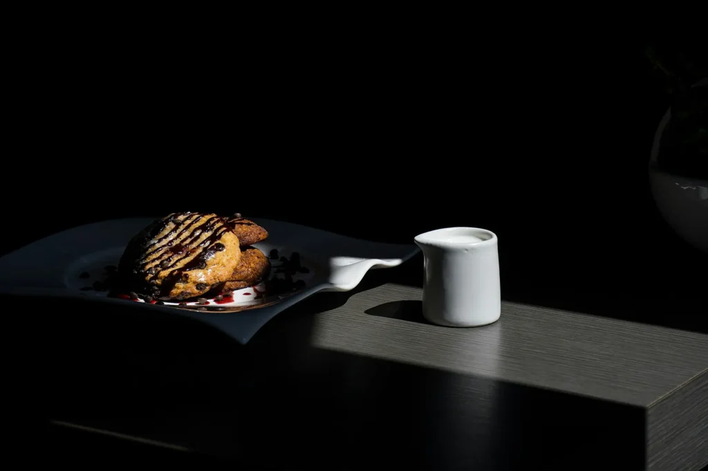 Dark moody food photography of chocolate chip cookies and milk on a restaurant menu.
