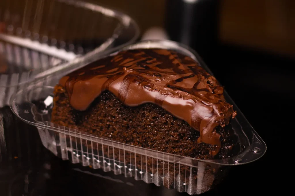 Slice of chocolate cake in a clear take-out container.