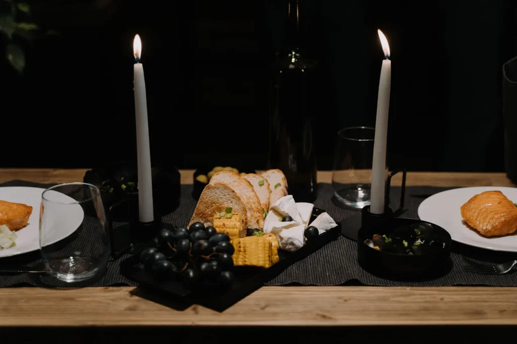 Candlelit fine dining table arrangement with food platters in a dark restaurant setting.