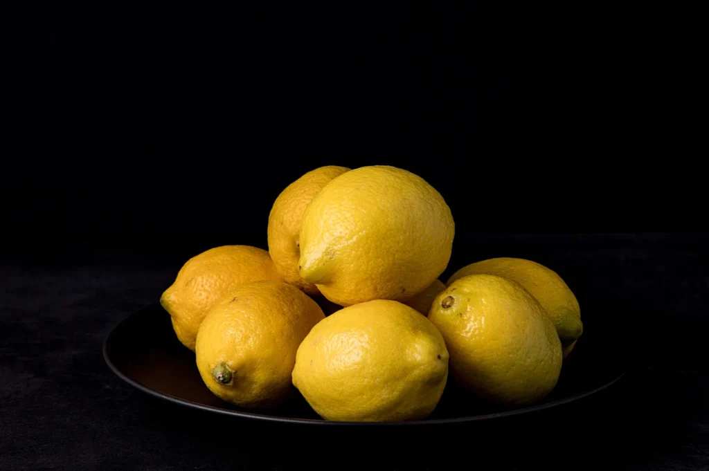 Fresh yellow lemons on a black plate with a dark background for cloud kitchen photography.