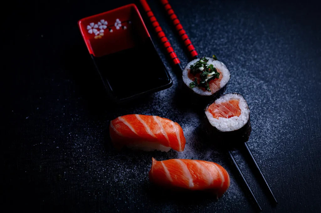 Dark moody food photography of fresh salmon sushi and maki on a black background.