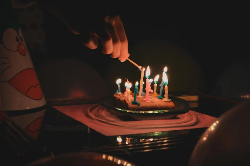 Child birthday celebration with cake and lit candles in a dark restaurant setting.