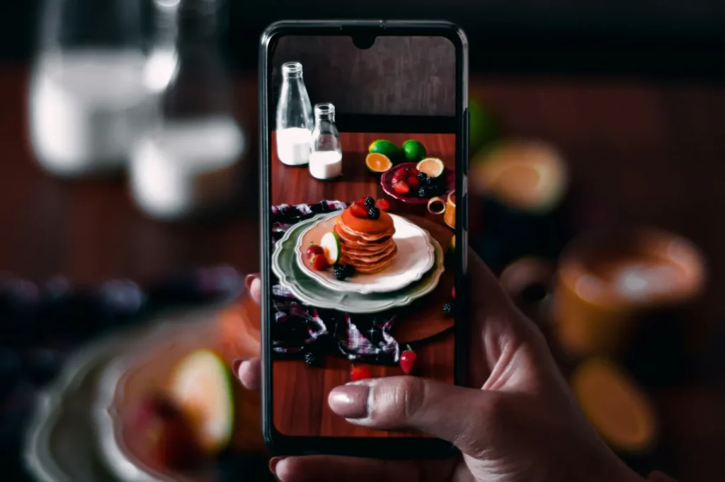 Person using a smartphone to take a photo of food for a restaurant listing and digital marketing.