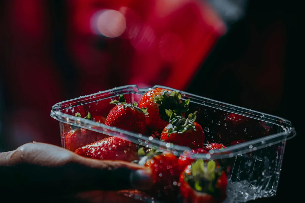 Fresh strawberries in a plastic container for takeaway photography.