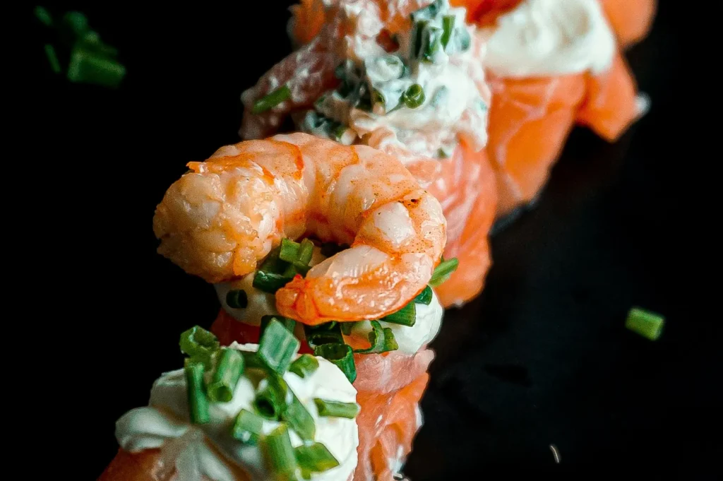 Dark and moody food photography of fresh shrimp and salmon seafood on a black background.