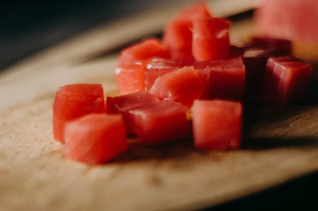 Fresh cubed raw tuna on a wooden cutting board.