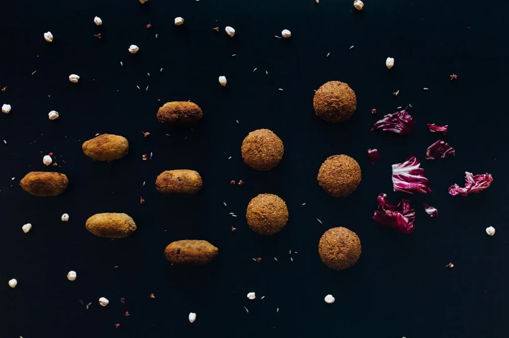 Plant-based falafel and chickpeas arranged on a dark background.