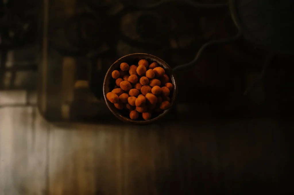 Overhead view of a small bowl filled with crispy snacks on a dark moody table.