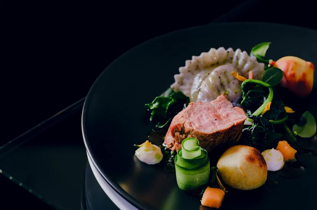 Dark and moody gourmet plated dish with negative space for text on a black background.
