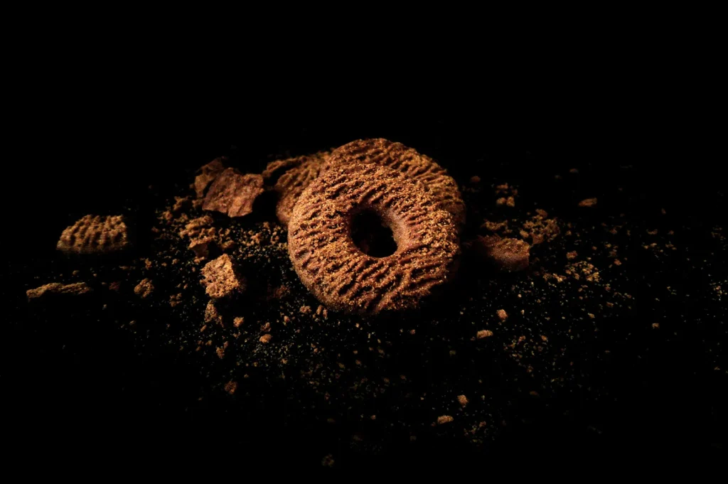 Dark moody food photography of artisanal cookies and pastry crumbs on a black background.
