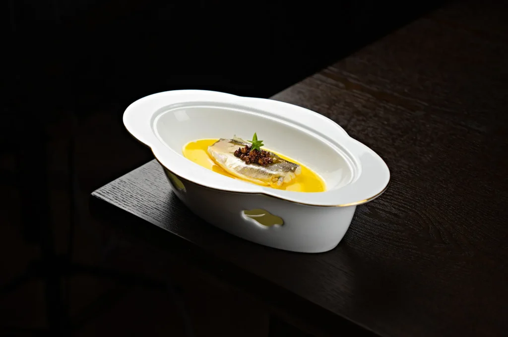 Teochew-style clear fish soup in a white bowl on a dark table.