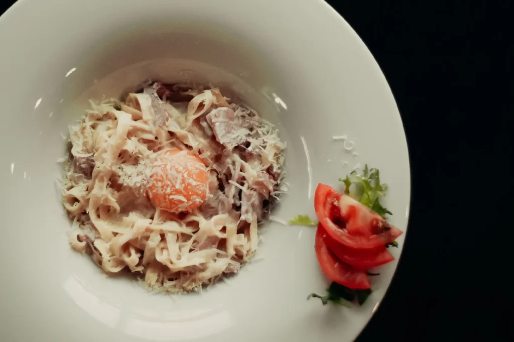 Gourmet pasta with egg yolk served on a white plate.