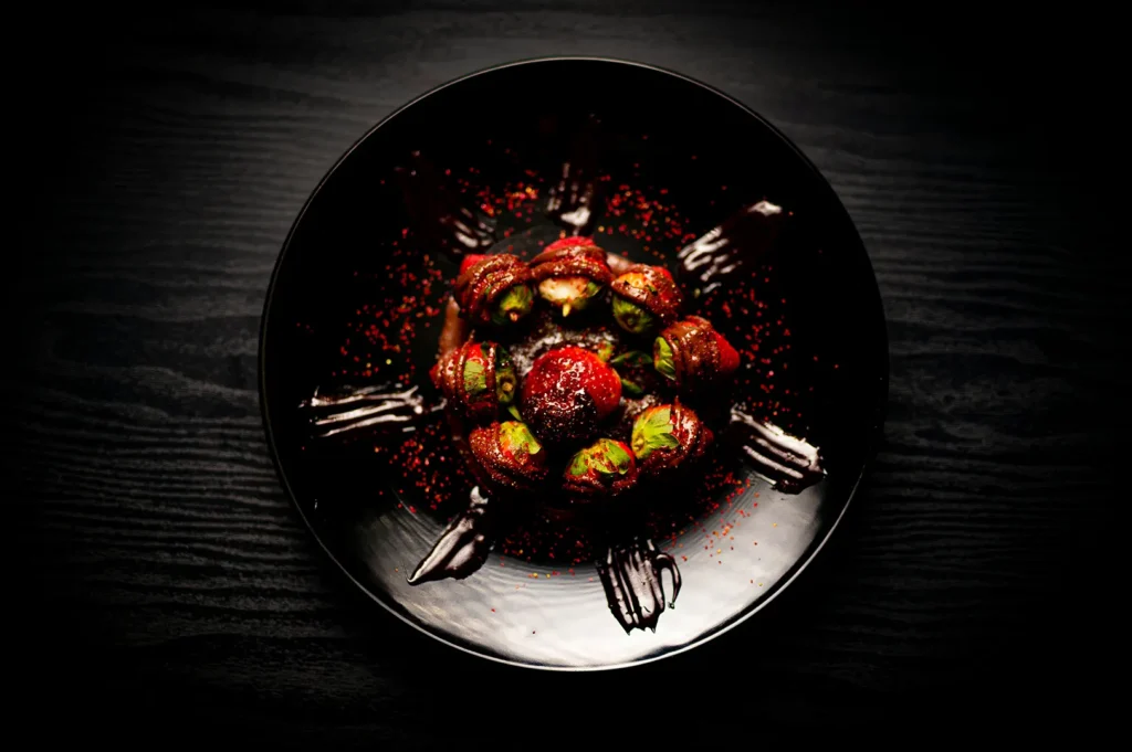 Dark food photography of chocolate dessert with strawberries on a black plate.