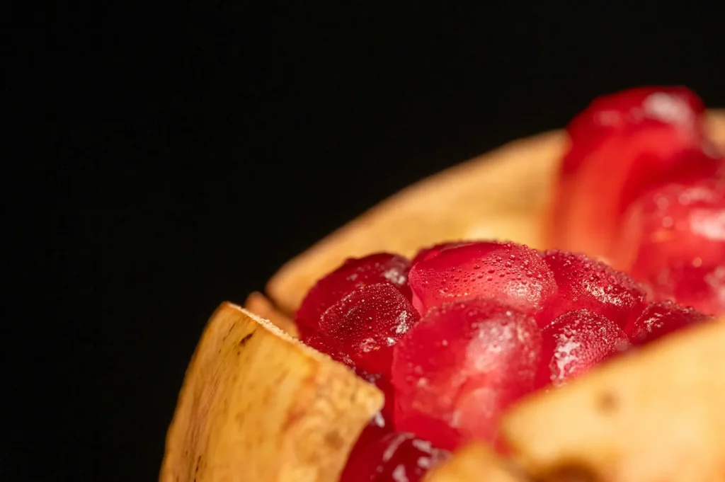 Close-up shot of fresh vibrant pomegranate seeds on a dark background.