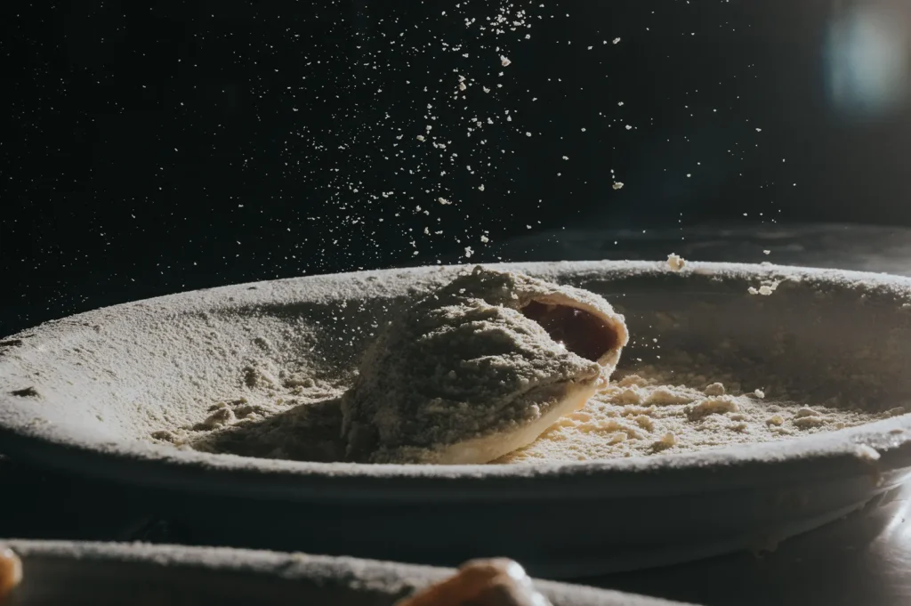 Dark moody food photography of a dish being served with cascading powder toppings in a Singapore restaurant.